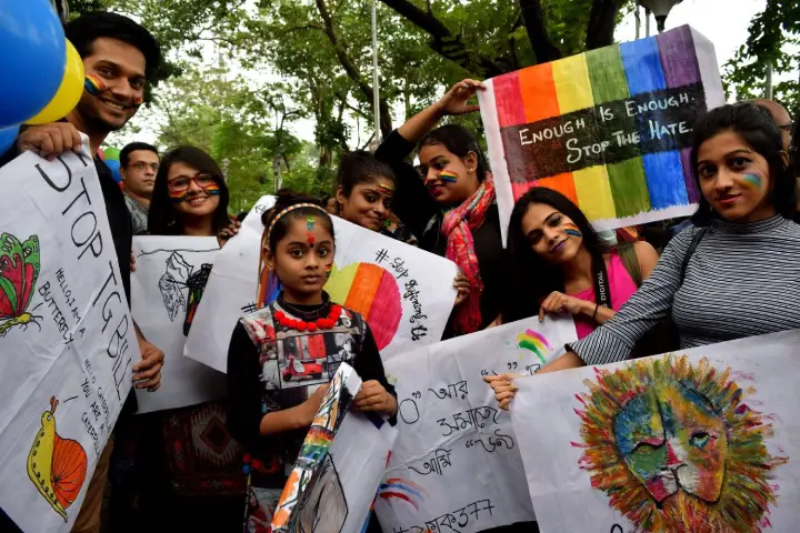 Participants at a pride event holding rainbow flags and LGBTIQ+ placards